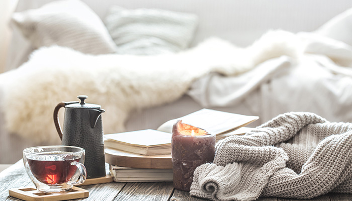 Coffee table with teapot, glass mug, candle and books with a couch backdrop